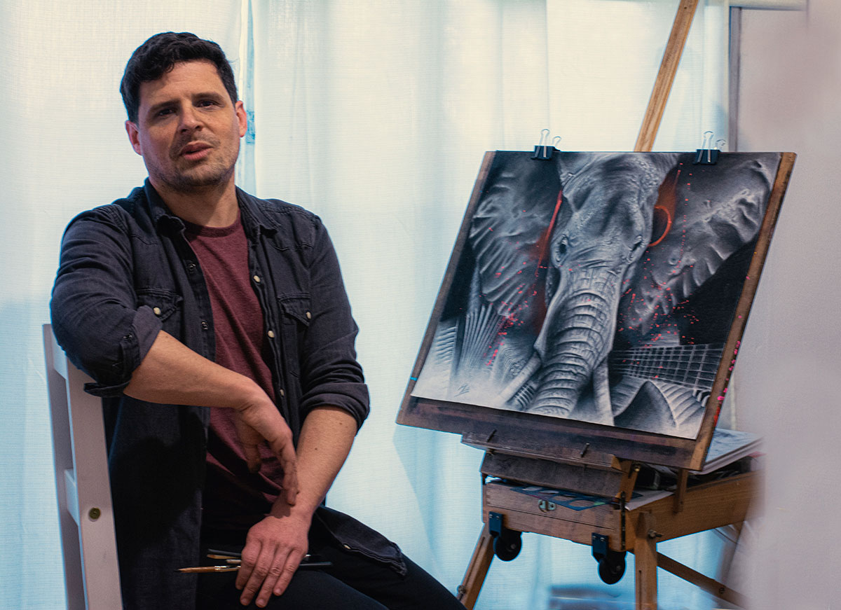 Foto del artista Martin Mailhe junto una de sus obras, en este caso un dibujo al detalle de un elefante